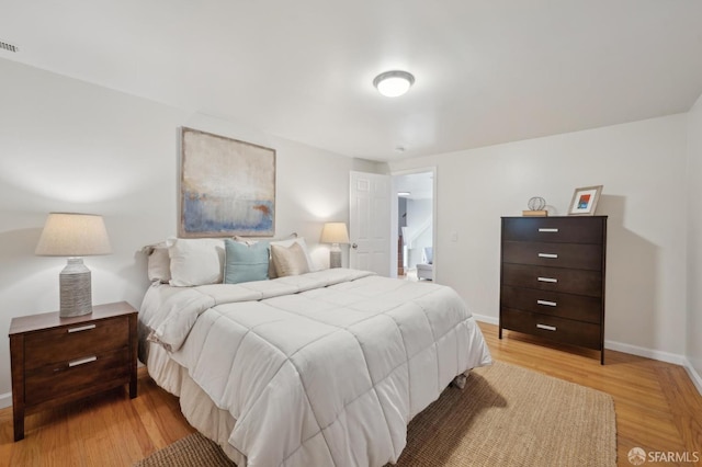 bedroom featuring light wood-type flooring, visible vents, and baseboards