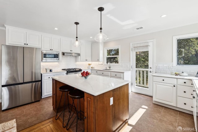 kitchen with visible vents, under cabinet range hood, appliances with stainless steel finishes, white cabinetry, and a sink