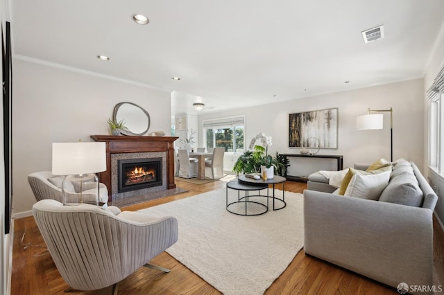 living room featuring wood finished floors, visible vents, recessed lighting, a high end fireplace, and ornamental molding