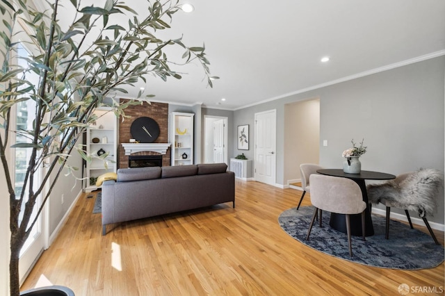 living room featuring light wood finished floors, a fireplace, baseboards, and ornamental molding