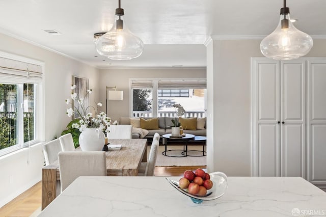 dining room featuring a wealth of natural light, light wood-style flooring, visible vents, and ornamental molding