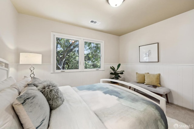 bedroom with a wainscoted wall, carpet, and visible vents