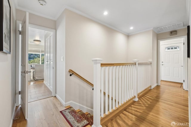 hall with wood finished floors, crown molding, recessed lighting, and an upstairs landing