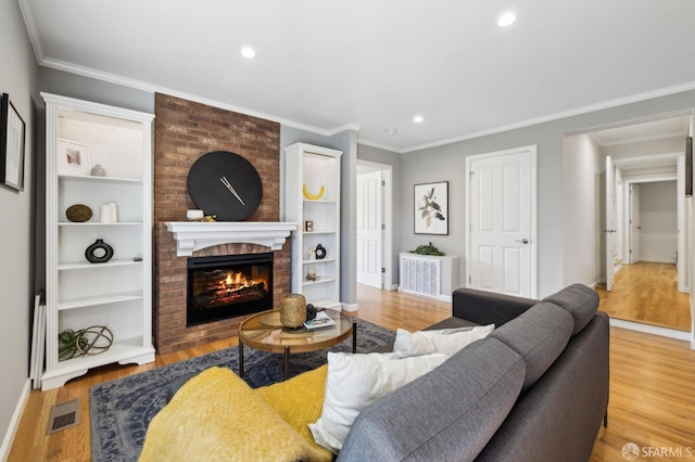 living room featuring visible vents, wood finished floors, a fireplace, and crown molding