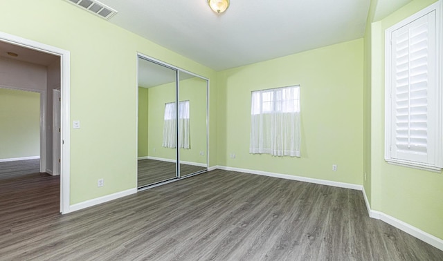 unfurnished bedroom featuring baseboards, visible vents, wood finished floors, and a closet
