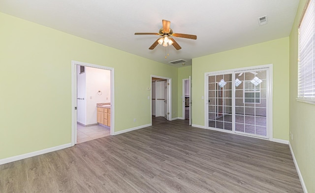 unfurnished room with visible vents, a ceiling fan, baseboards, and wood finished floors