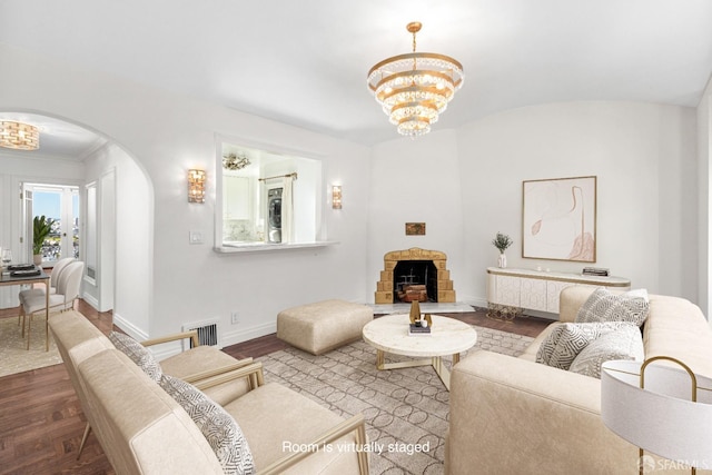 living room featuring arched walkways, baseboards, an inviting chandelier, and wood finished floors