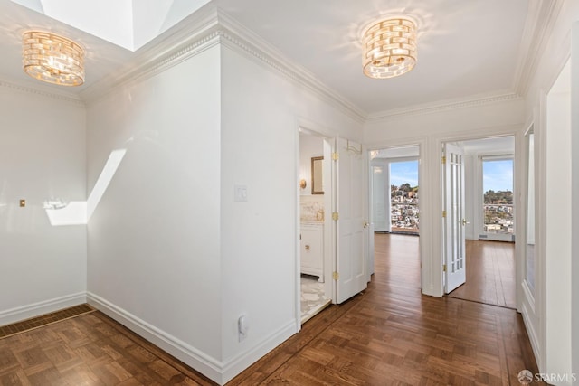 hall featuring baseboards, a chandelier, and ornamental molding