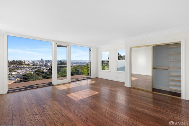 interior space featuring ornamental molding, expansive windows, baseboards, and wood finished floors