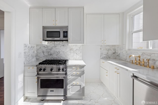 kitchen with a sink, stainless steel appliances, backsplash, and white cabinetry