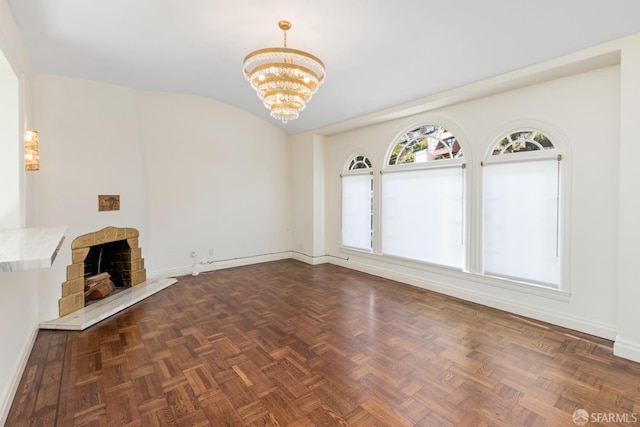 unfurnished living room featuring an inviting chandelier, a fireplace with raised hearth, baseboards, and vaulted ceiling