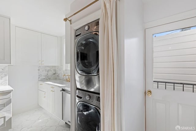 washroom featuring a sink, stacked washer and dryer, and laundry area