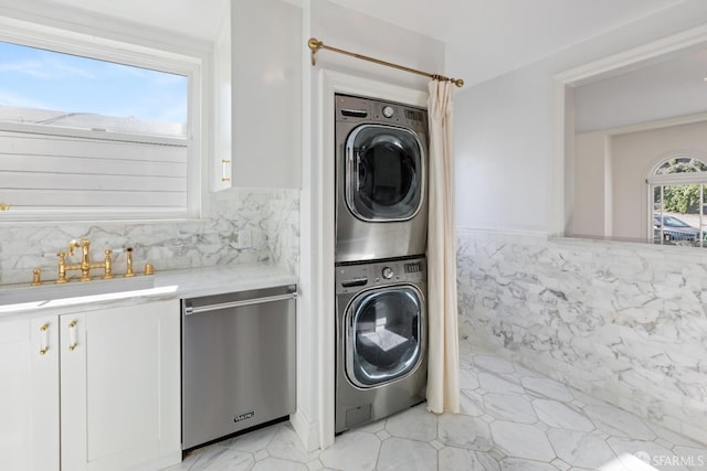 laundry room with a sink, tile walls, stacked washer and clothes dryer, and laundry area