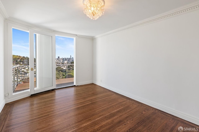 empty room with baseboards, an inviting chandelier, dark wood-style flooring, crown molding, and a view of city