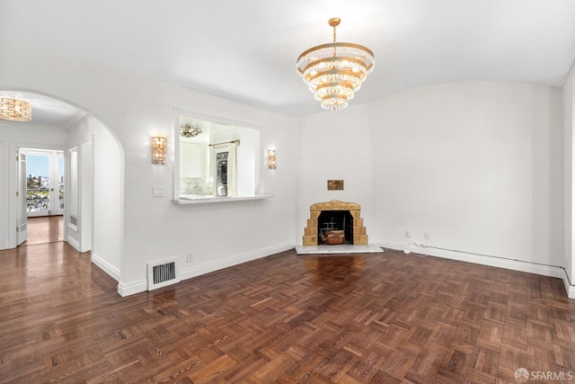 unfurnished living room with visible vents, baseboards, a stone fireplace, arched walkways, and a notable chandelier