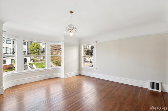 empty room featuring an inviting chandelier and hardwood / wood-style flooring