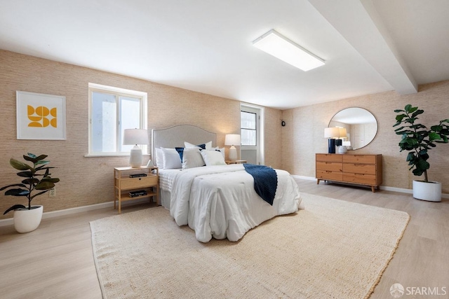 bedroom featuring beamed ceiling, baseboards, and wood finished floors