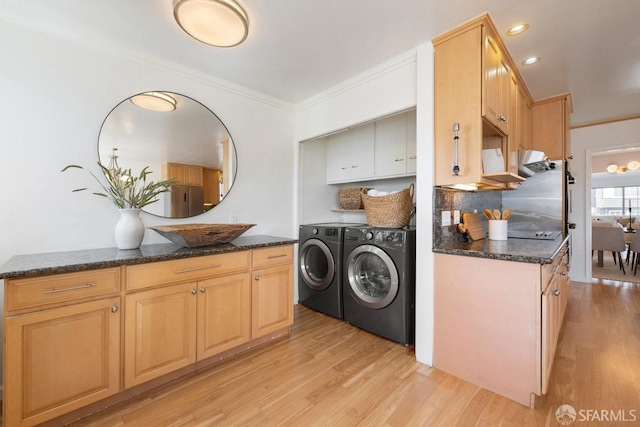 laundry room featuring crown molding, cabinet space, light wood finished floors, and washing machine and clothes dryer