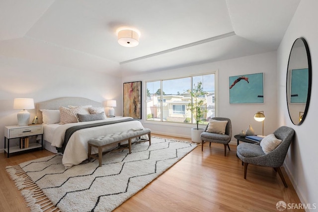 bedroom with baseboards, a tray ceiling, and wood finished floors