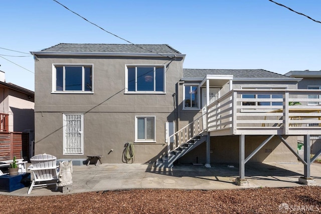 rear view of house featuring a patio, stairway, a wooden deck, stucco siding, and a shingled roof