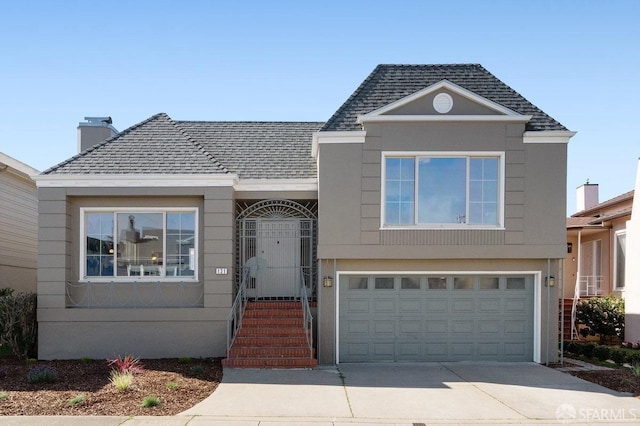 split level home featuring a garage, concrete driveway, and a shingled roof