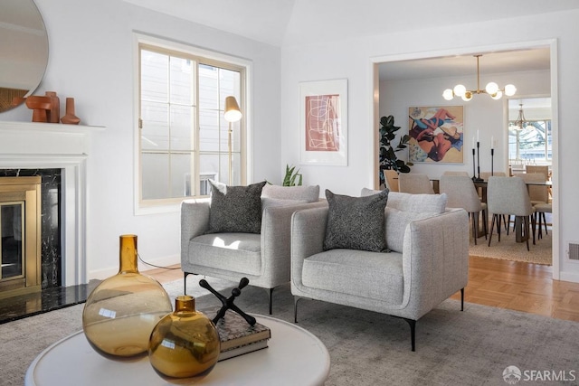 living area with visible vents, an inviting chandelier, and a high end fireplace