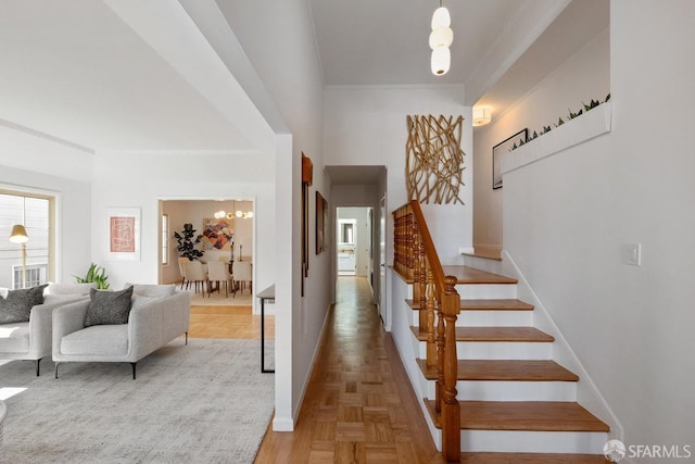 foyer entrance featuring a chandelier, stairs, baseboards, and ornamental molding