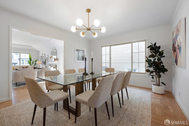 dining area with ornamental molding, a fireplace, baseboards, and a chandelier