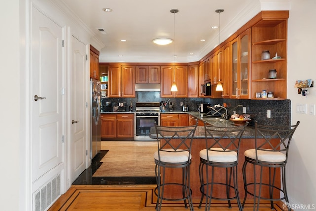 kitchen featuring a kitchen bar, tasteful backsplash, hanging light fixtures, appliances with stainless steel finishes, and kitchen peninsula