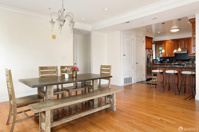 dining area featuring an inviting chandelier, crown molding, and light hardwood / wood-style flooring