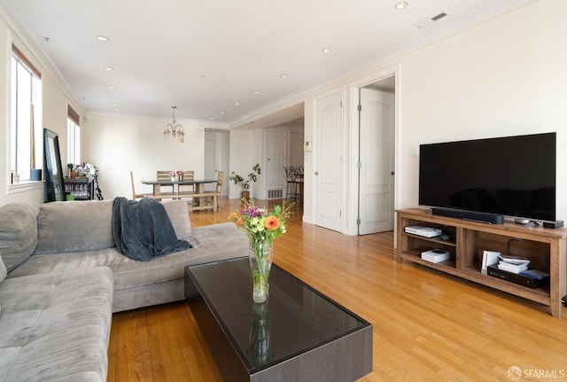 living room with wood-type flooring, crown molding, and a chandelier