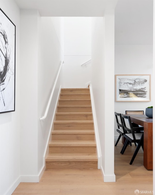 staircase featuring baseboards and wood finished floors