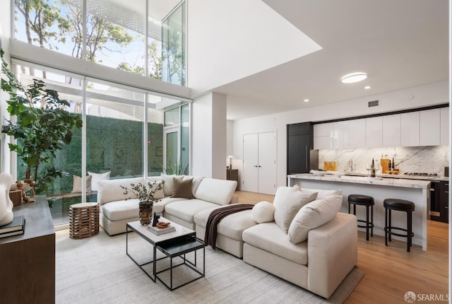 living area featuring a high ceiling, visible vents, and light wood-type flooring