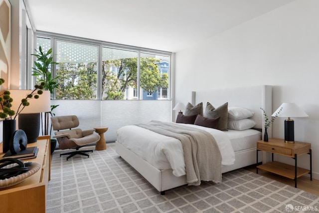 bedroom with light wood-style flooring and expansive windows