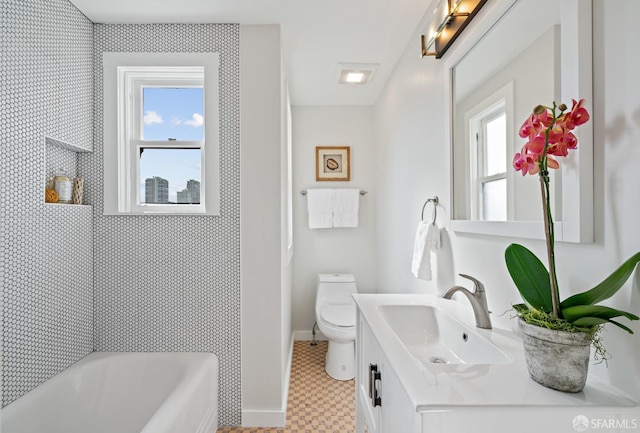 bathroom featuring a tub to relax in, a healthy amount of sunlight, vanity, and toilet