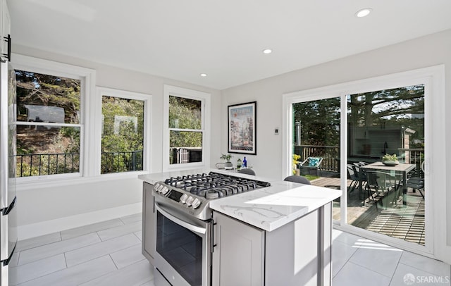 kitchen featuring light tile patterned flooring, light stone countertops, and stainless steel gas range