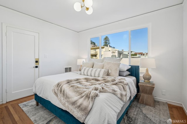 bedroom featuring an inviting chandelier and wood-type flooring