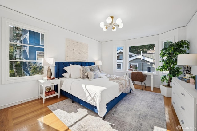 bedroom featuring multiple windows, a chandelier, and light hardwood / wood-style flooring