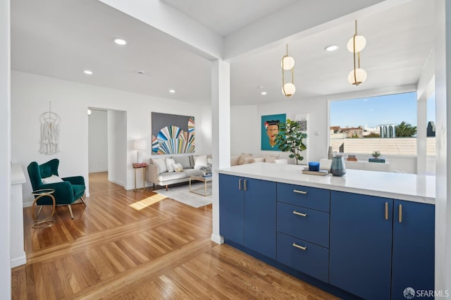 kitchen with blue cabinets, hanging light fixtures, and wood-type flooring