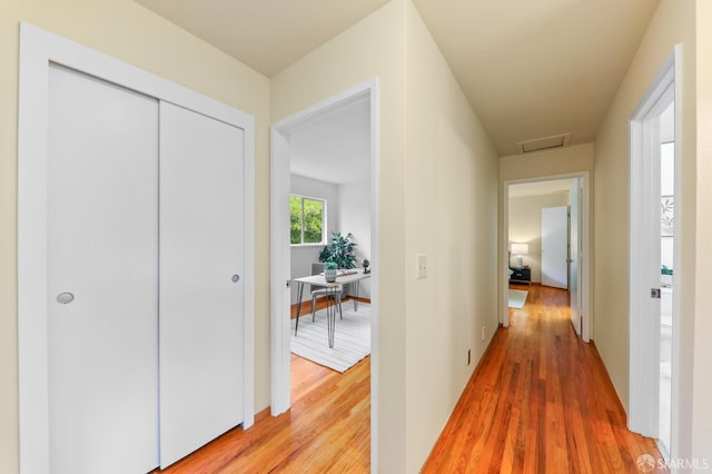 hallway with light wood-type flooring and attic access
