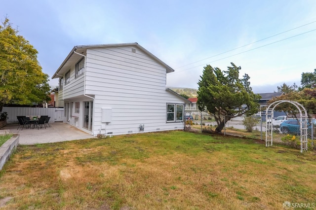 view of side of home featuring fence, a yard, and a patio area