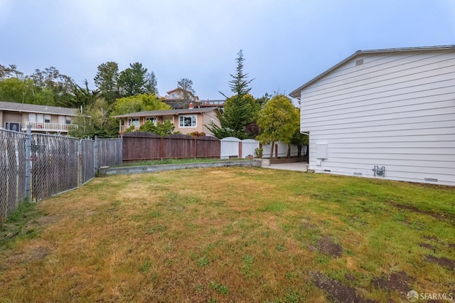 view of yard featuring a fenced backyard, an outdoor structure, and a shed