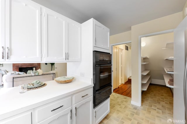 kitchen featuring white cabinets, oven, a warming drawer, and light countertops