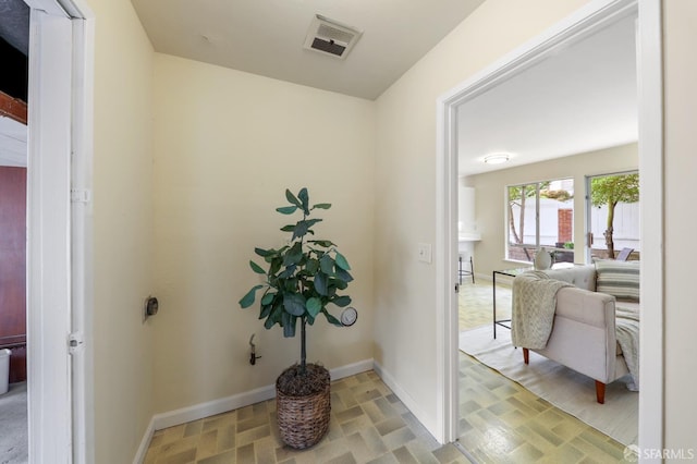hall featuring baseboards and visible vents