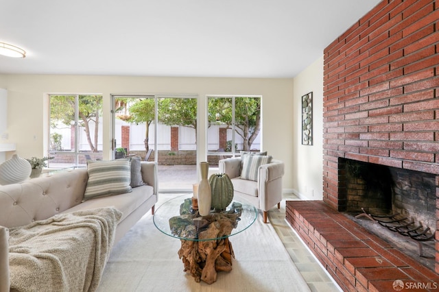 living room featuring plenty of natural light, baseboards, and a brick fireplace