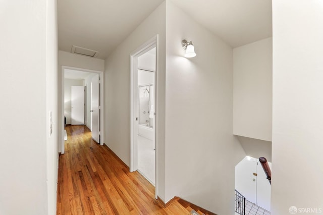 corridor featuring light wood-type flooring, attic access, and an upstairs landing