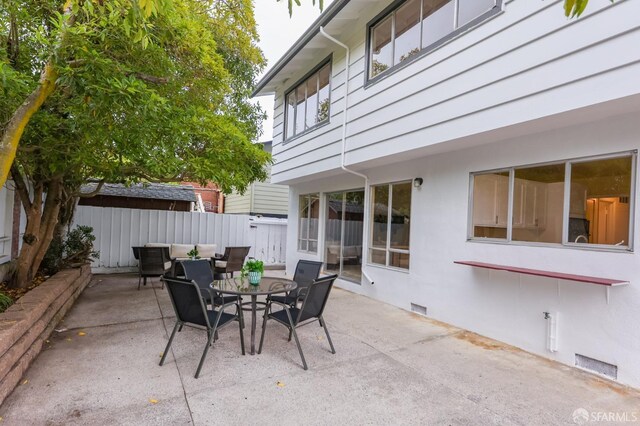view of patio featuring fence, outdoor dining area, and visible vents