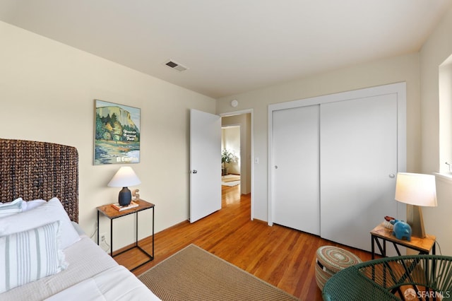 bedroom with a closet, light wood finished floors, and visible vents
