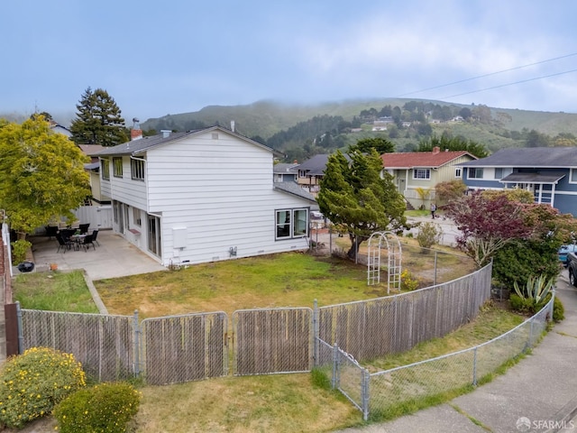 view of home's exterior with a lawn, a mountain view, a fenced backyard, and a patio area