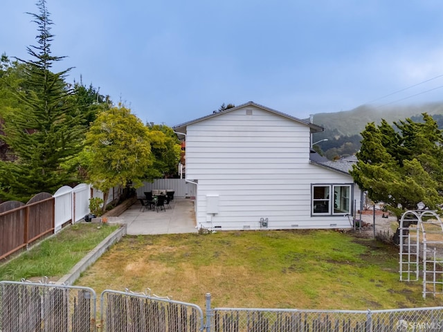 back of property featuring a lawn, a mountain view, a fenced backyard, and a patio area